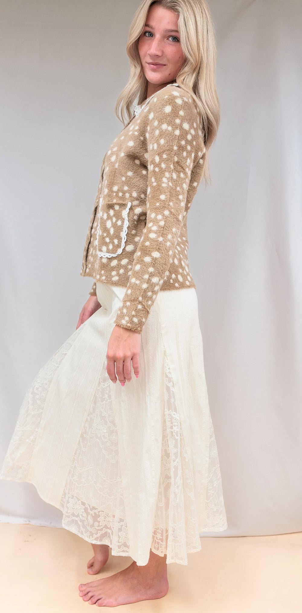 Woman shown from side view wearing fawn print jacket with lace detail maxi skirt on plain background