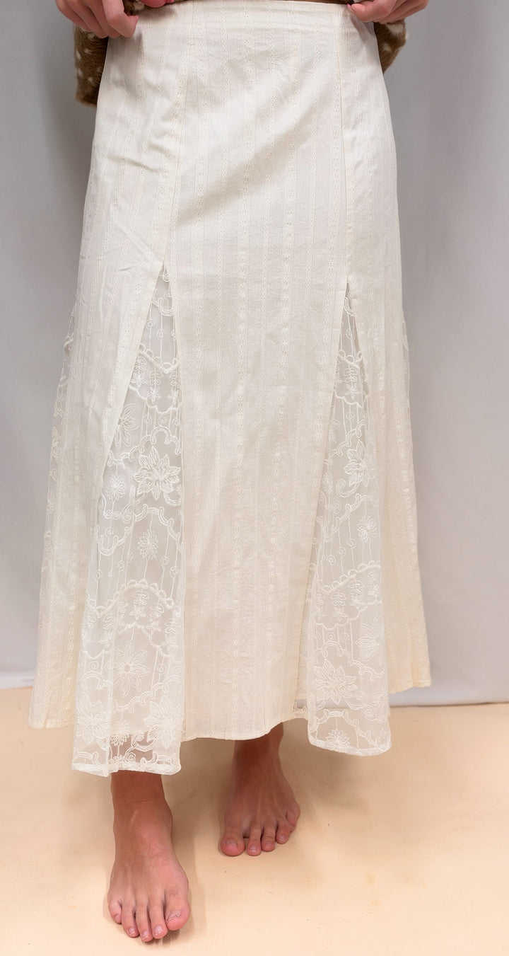 Woman shown from waist down wearing lace detail maxi skirt on plain background
