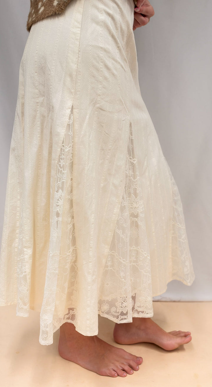 Woman shown from side view wearing lace detail maxi skirt on plain background