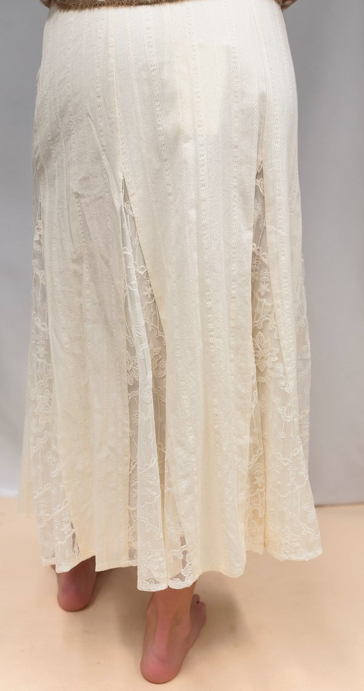Woman shown from back view wearing lace detail maxi skirt on plain background