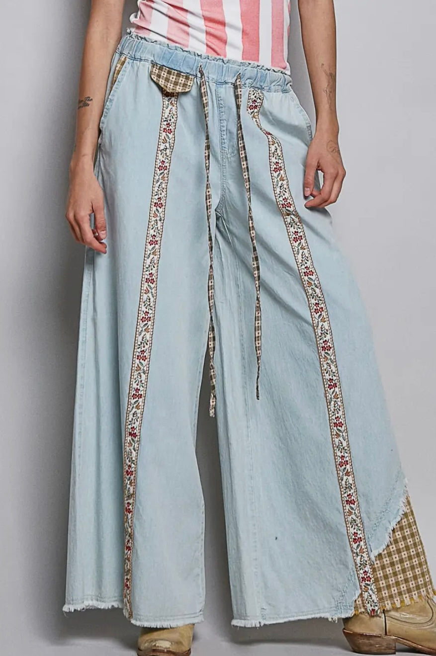 Light blue denim pants with patterned trim worn by a person on a plain background