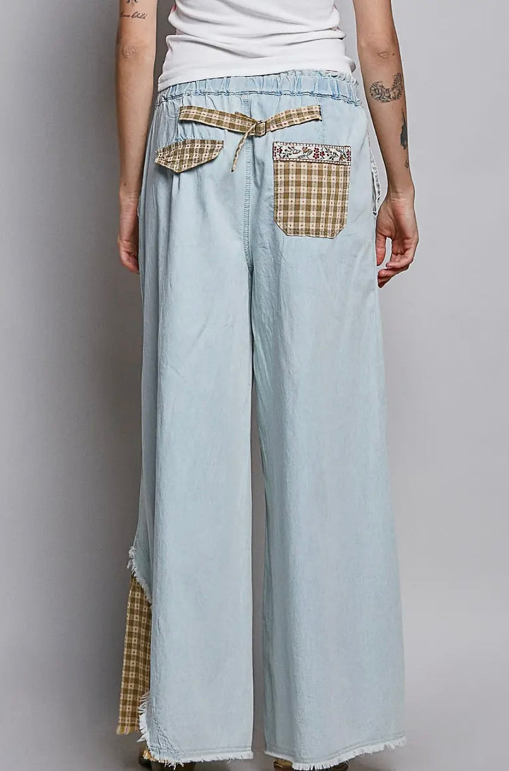 Light blue denim pants with plaid accents worn by a person on a plain background