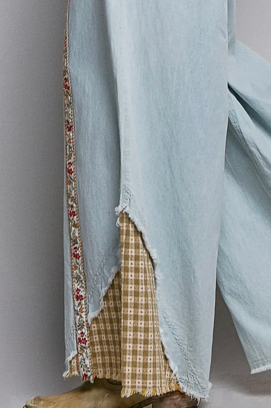 Light blue garment with floral trim and plaid lining on a neutral background
