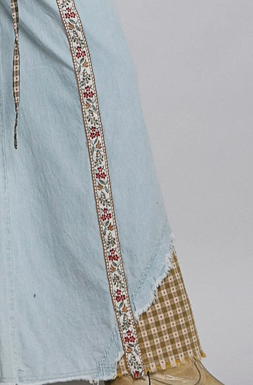 Light blue denim skirt with decorative trim on a plain background