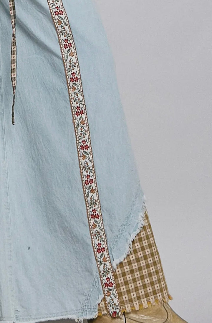 Light blue denim skirt with decorative trim on a plain background