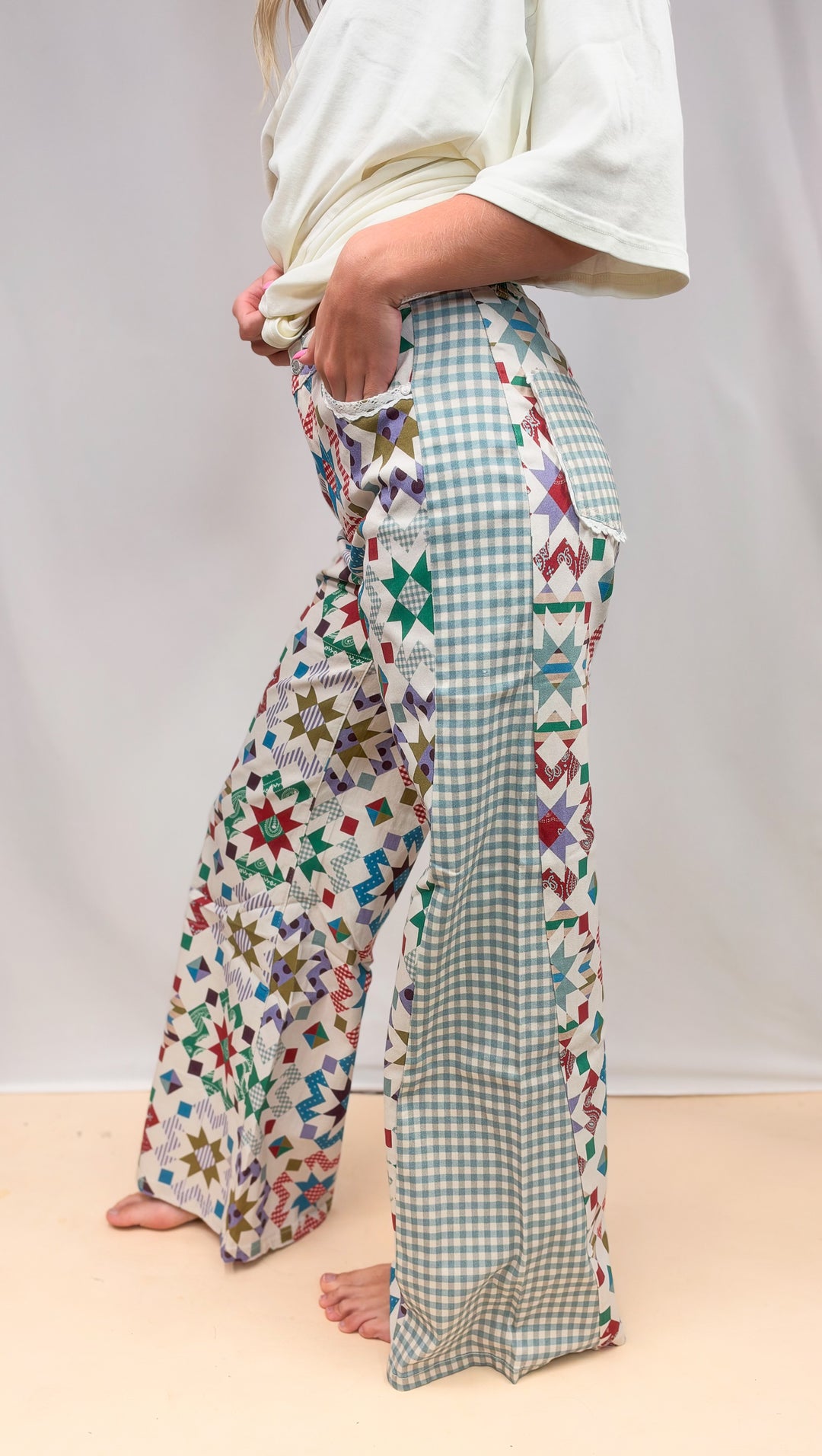 Side view of woman wearing quilted pattern pants with gingham detail on plain background