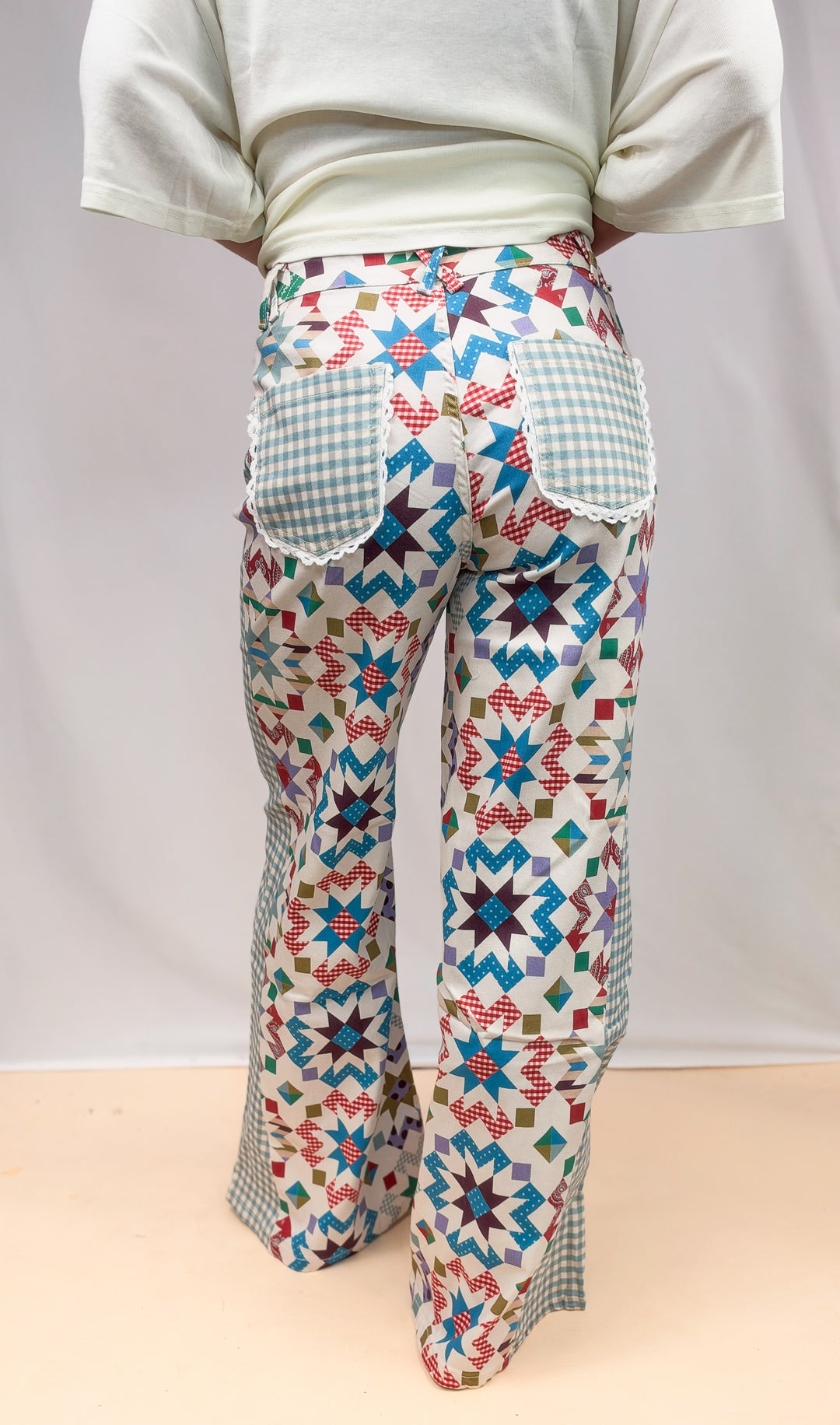 Woman shown from back wearing quilted pattern pants with gingham details on plain background