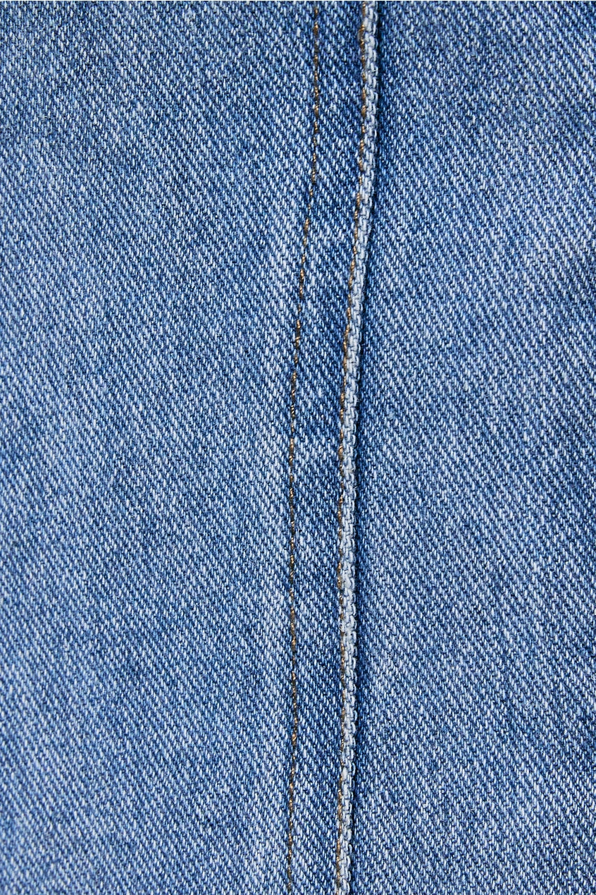 Close-up of blue denim fabric with a visible seam.