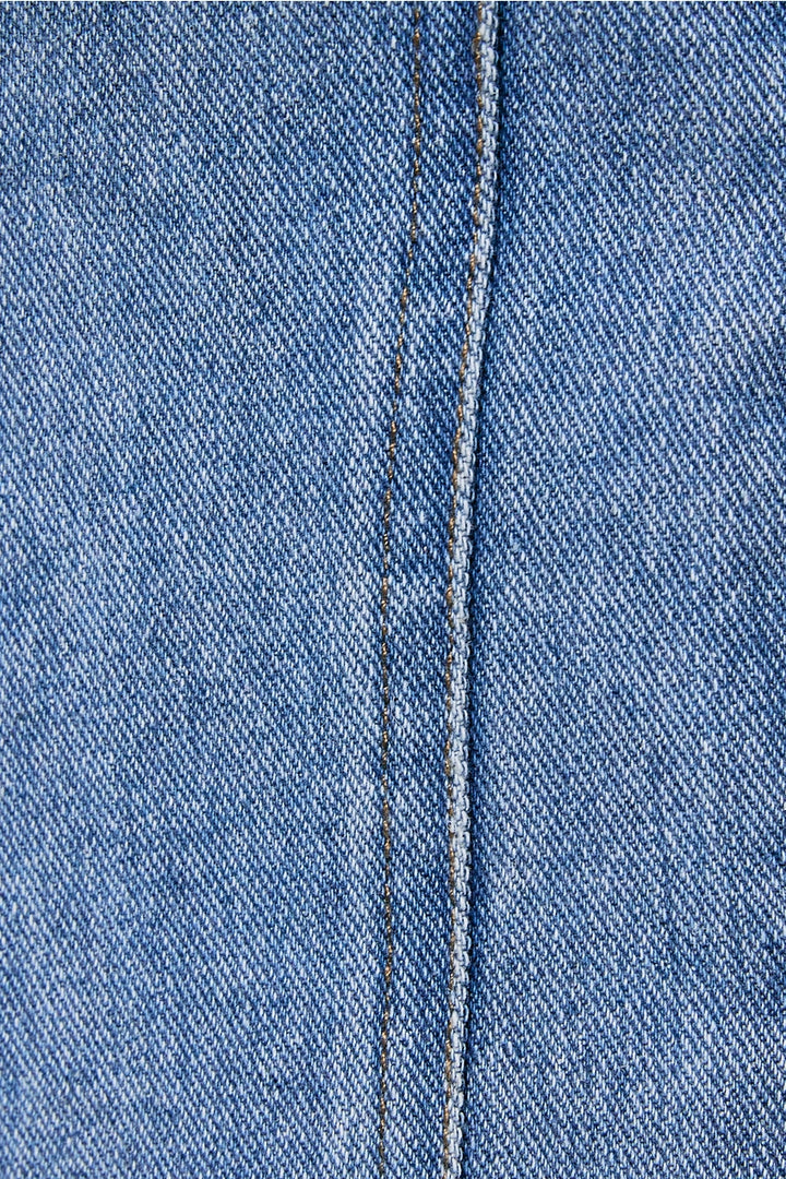 Close-up of blue denim fabric with a visible seam.