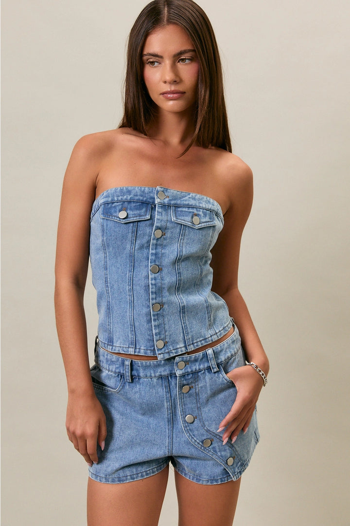 Woman wearing a denim strapless top and shorts set on a neutral background