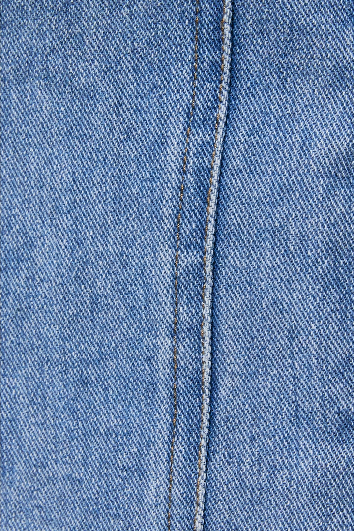 Close-up of blue denim fabric with a visible seam.