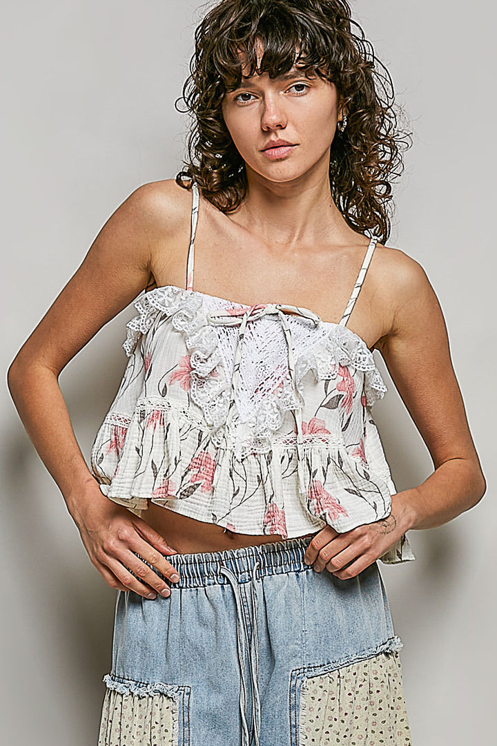 Woman wearing a floral top and denim pants against a plain background