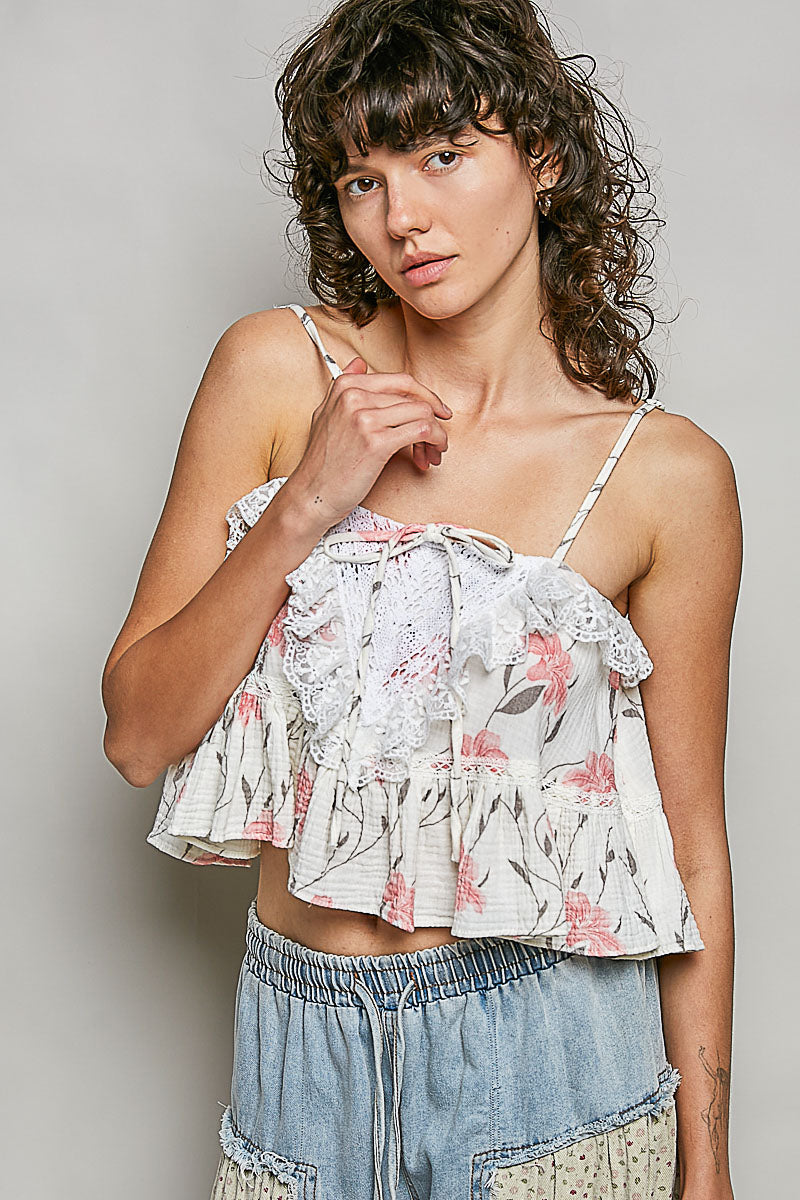 Woman wearing a floral top and denim shorts against a plain background