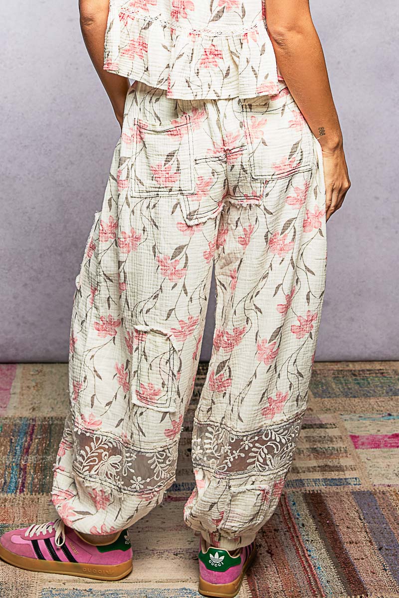 Person wearing floral pants and colorful shoes on a patterned rug.