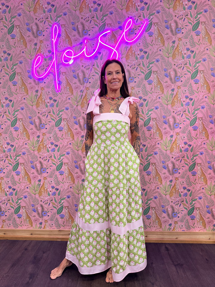 Woman wearing green and pink floral print dress on pink floral background