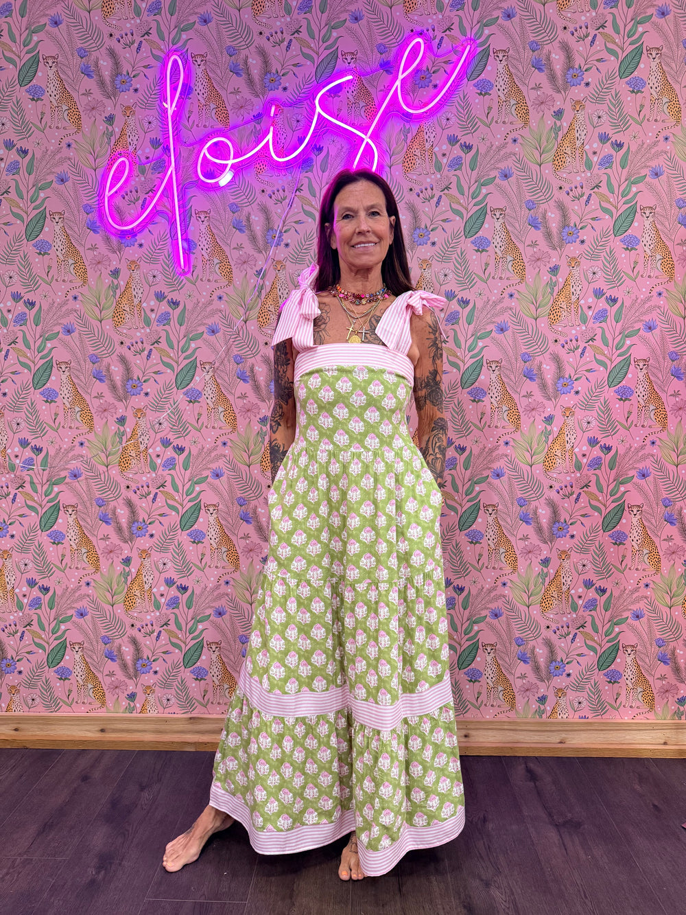 Woman wearing green and pink floral dress on pink floral background