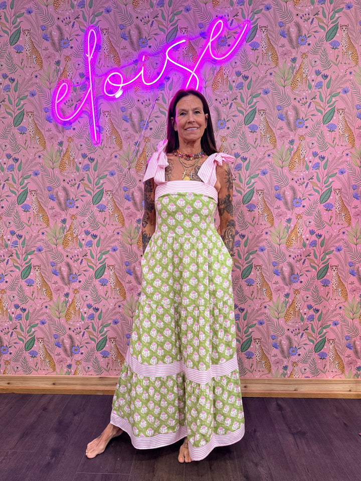 Woman wearing green and pink floral dress on pink floral background