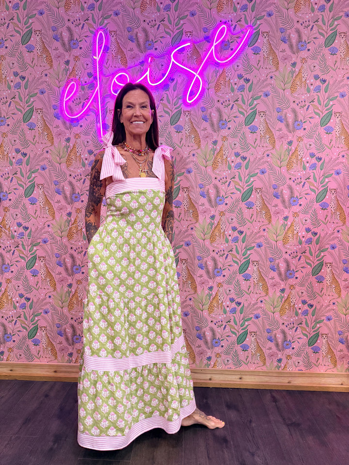 Woman wearing green and pink floral dress on pink floral background