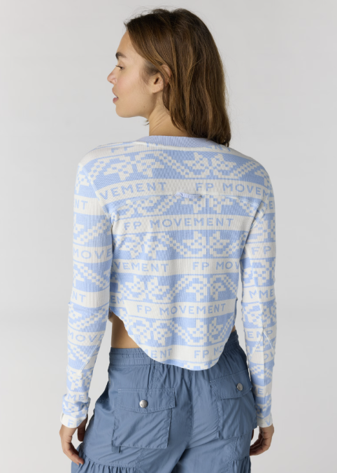 Woman shown from back wearing blue and white printed henley and blue pants on plain background
