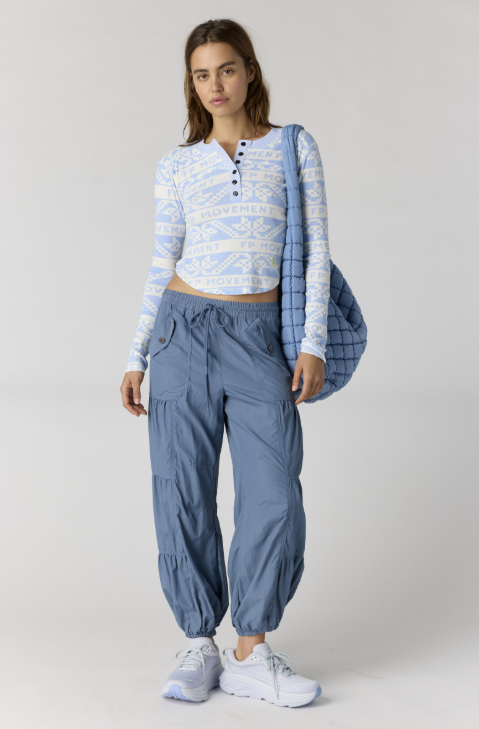 Woman wearing blue and white printed henley top with blue pants on white background