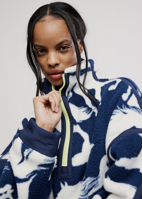 Woman wearing navy fleece jacket with white horse detail on plain background
