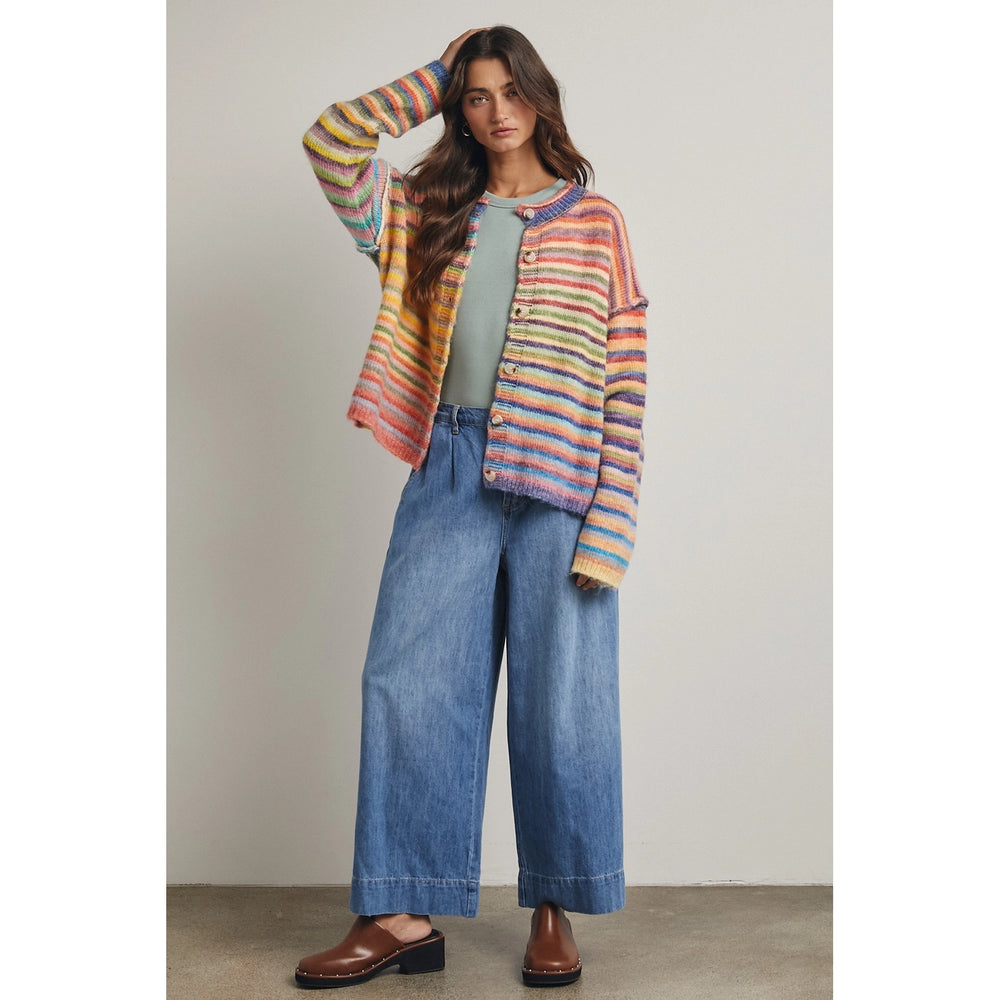 Woman wearing rainbow stripe cardigan with jeans on plain background