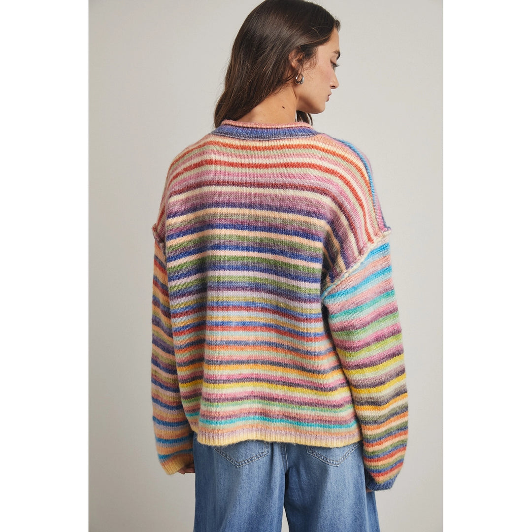 Back of woman wearing rainbow stripe cardigan on plain background