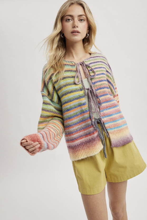 Woman wearing rainbow stripe cardigan on white background