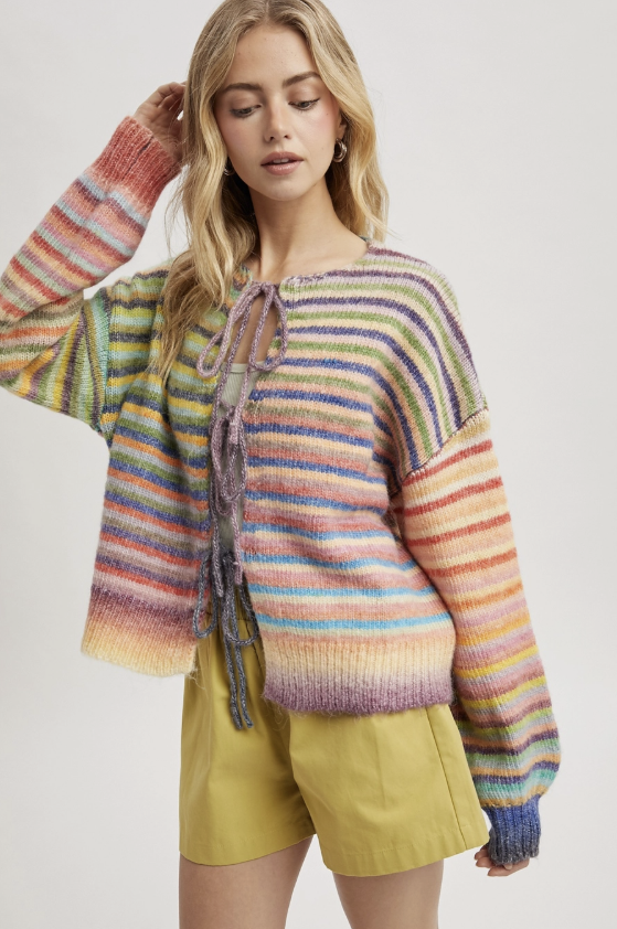 Woman wearing a colorful striped sweater with a plain background