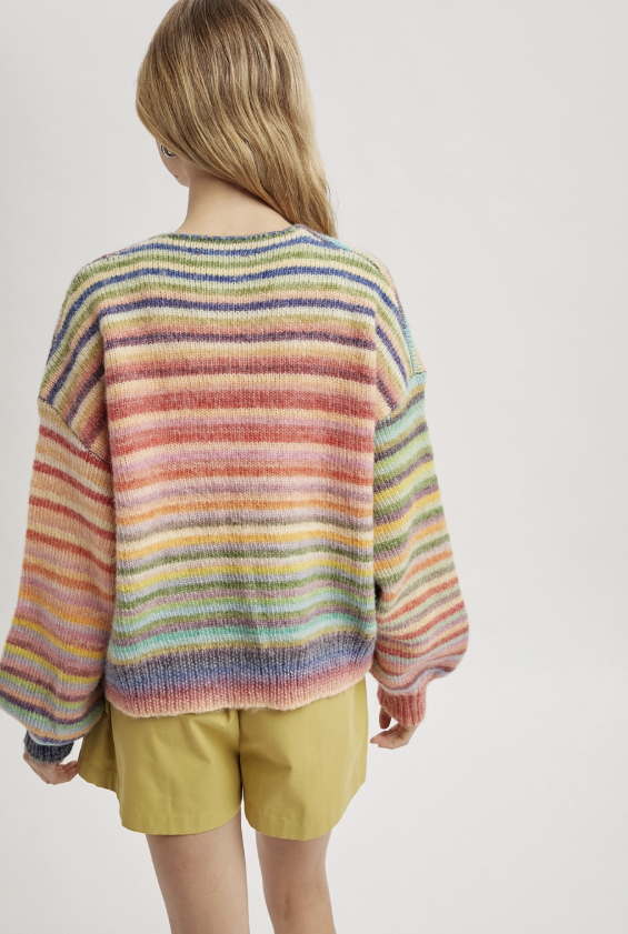 Person wearing a colorful striped sweater and yellow shorts on a plain background