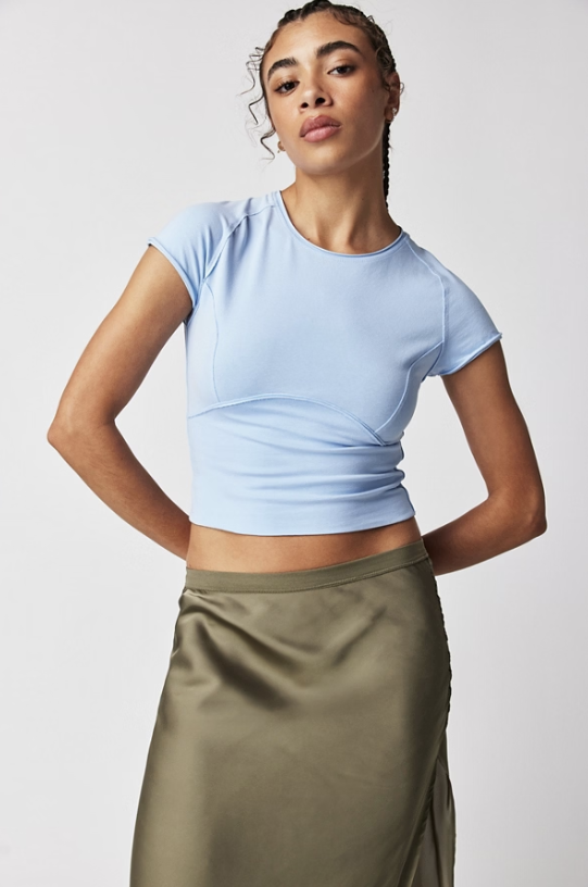 Woman wearing light blue tee with green skirt on white background