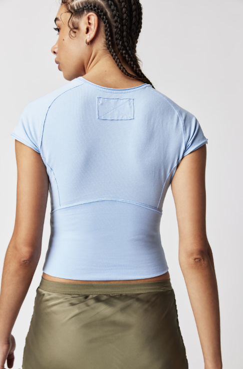 Person wearing a light blue crop top and green pants on a plain background