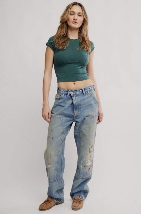 Woman wearing green tee and blue jeans on white background