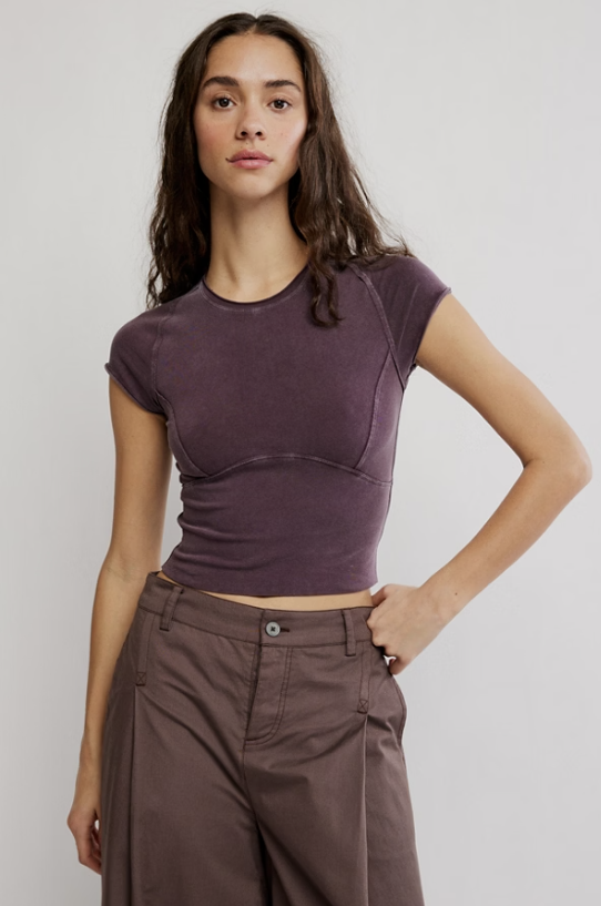 Woman wearing purple tee and brown pants on white background