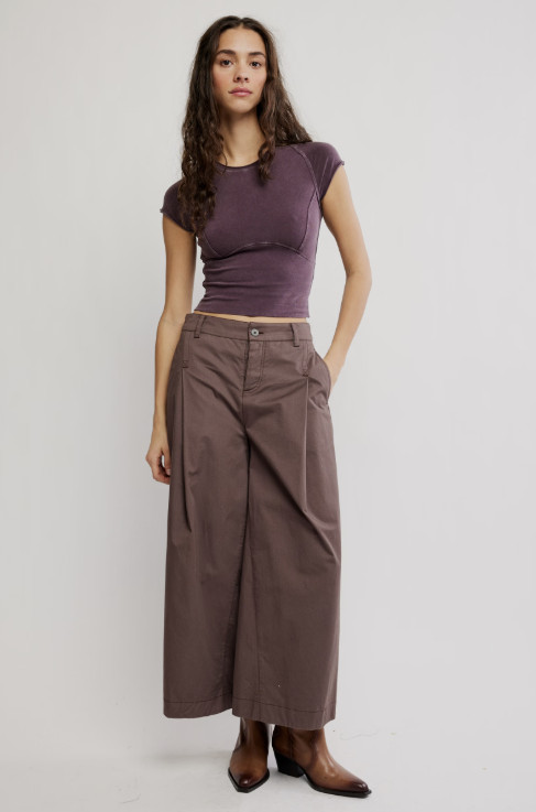 Woman wearing purple tee and brown pants on white background
