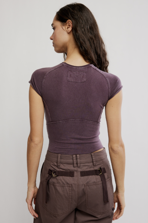 Woman wearing purple tee and brown pants on white background