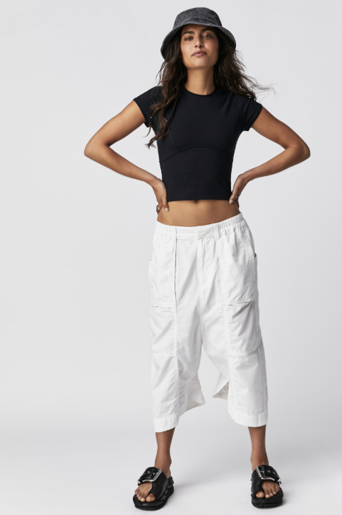 Woman wearing black tee and white pants on white background