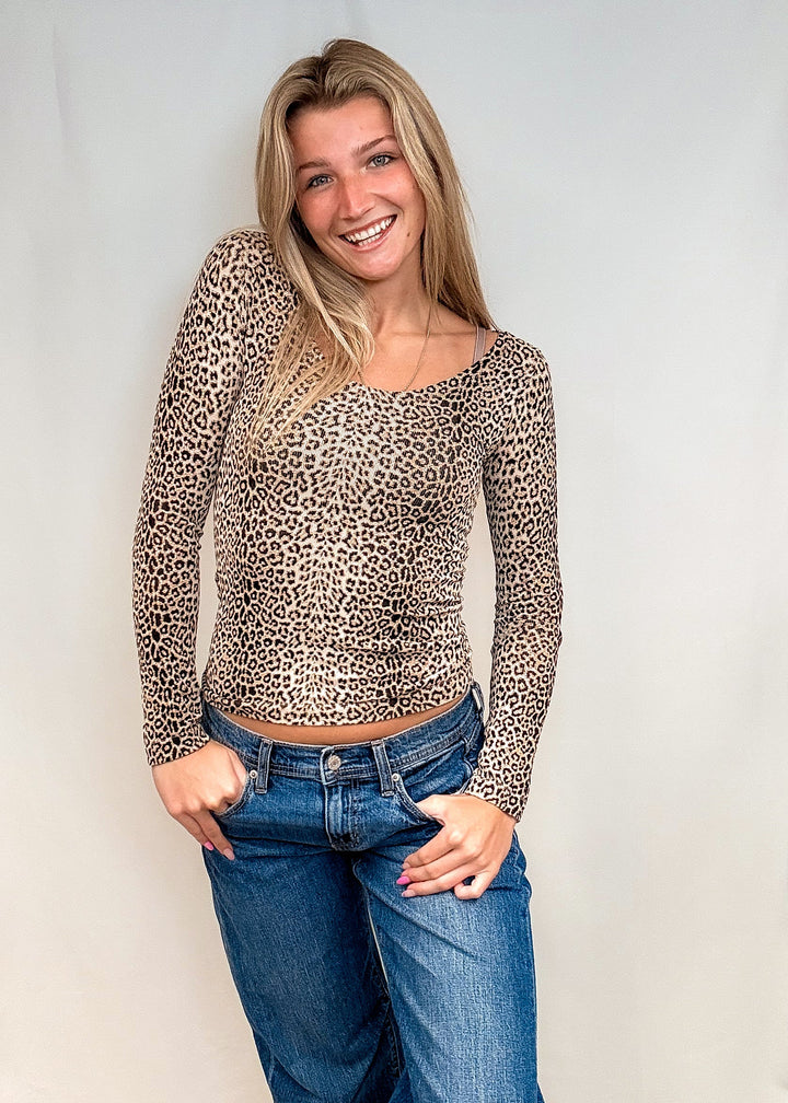 Woman wearing beige leopard print long sleeve with blue jeans on white background