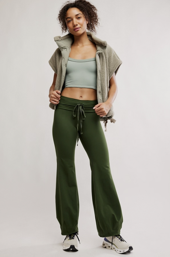 Woman wearing a green athletic outfit with a vest and pants on a white background