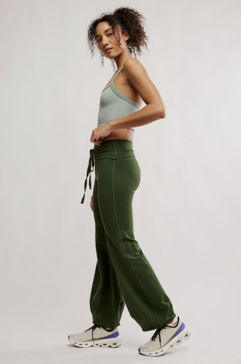 Woman wearing a green sports bra and pants on a light gray background