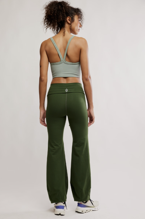Person wearing a green sports bra and pants on a plain background