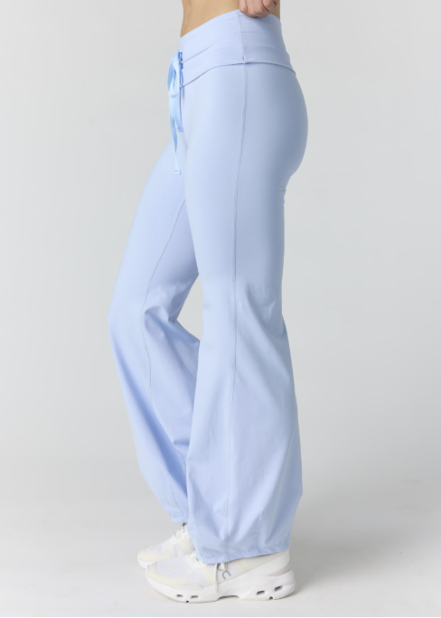 Woman wearing light blue tank and pants on plain background