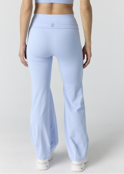 Woman shown from back wearing light blue tank and pants on plain background