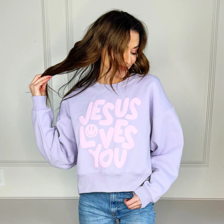 Woman wearing lilac sweatshirt that says &