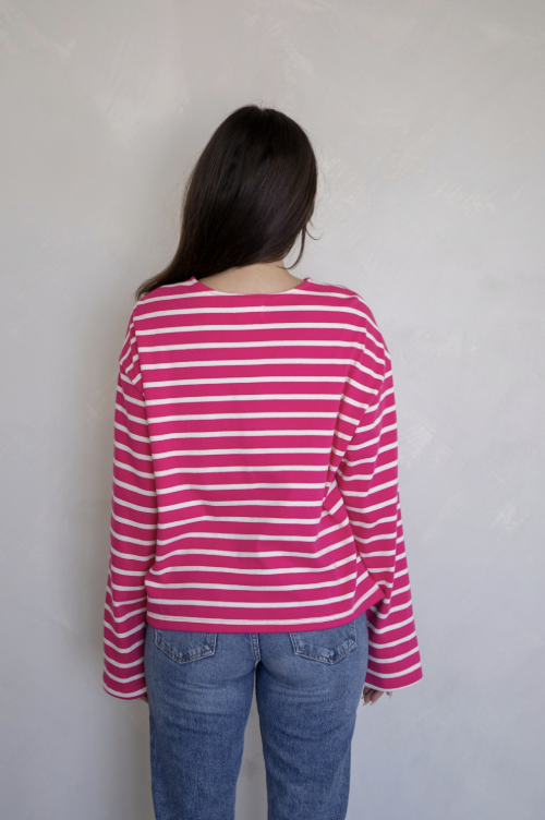 Woman shown from behind wearing pink and white stripe shirt and jeans on plain background