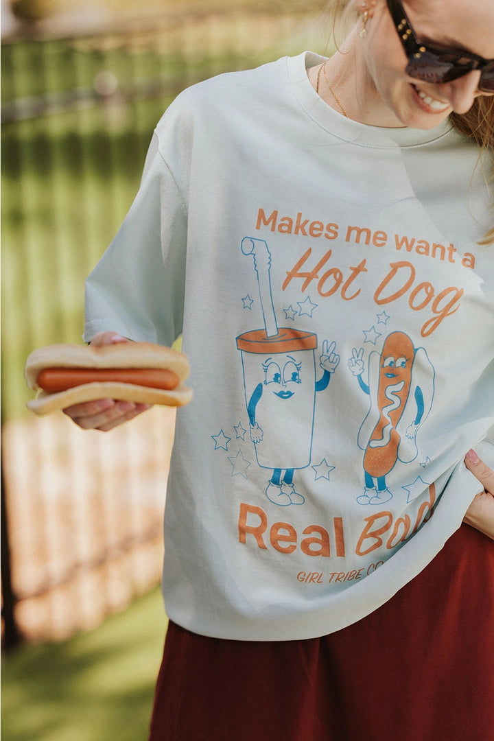 Woman wearing graphic tee with hot dog and drink standing outdoors