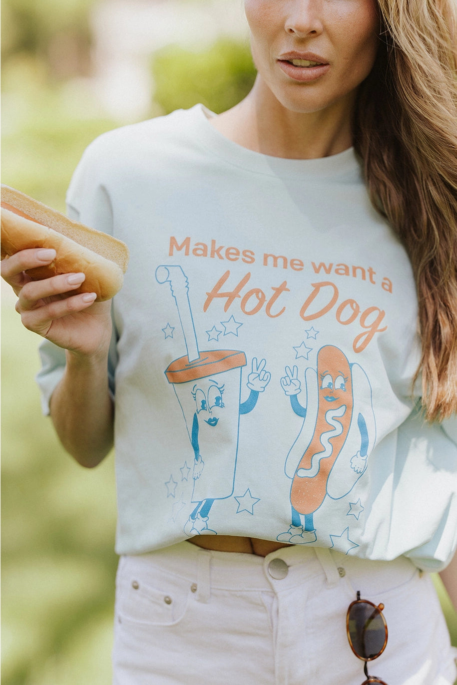 Woman wearing graphic tee with hot dog and drink standing outdoors