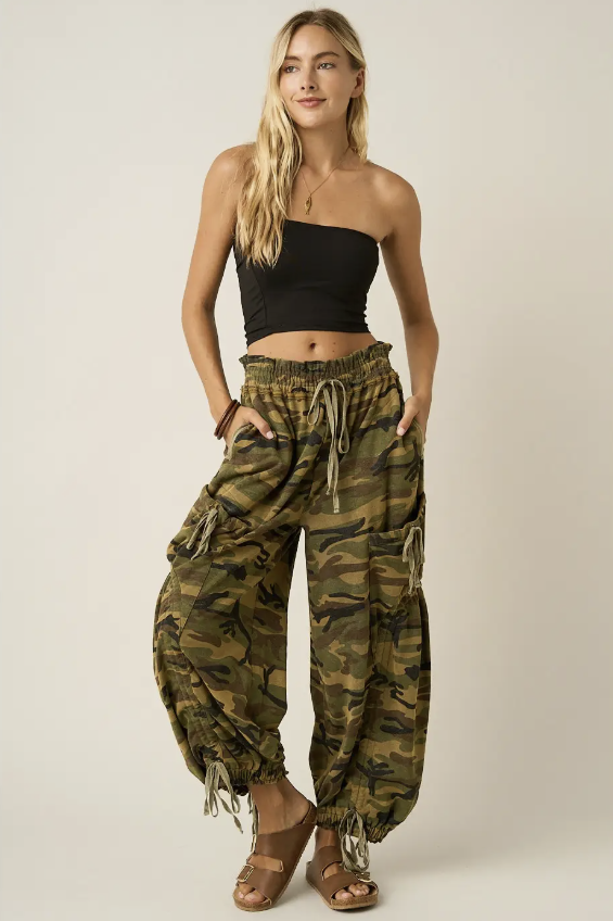 Woman wearing black tube top and camo pants on plain background