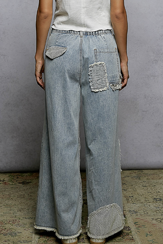Woman wearing patchwork jeans on plain background