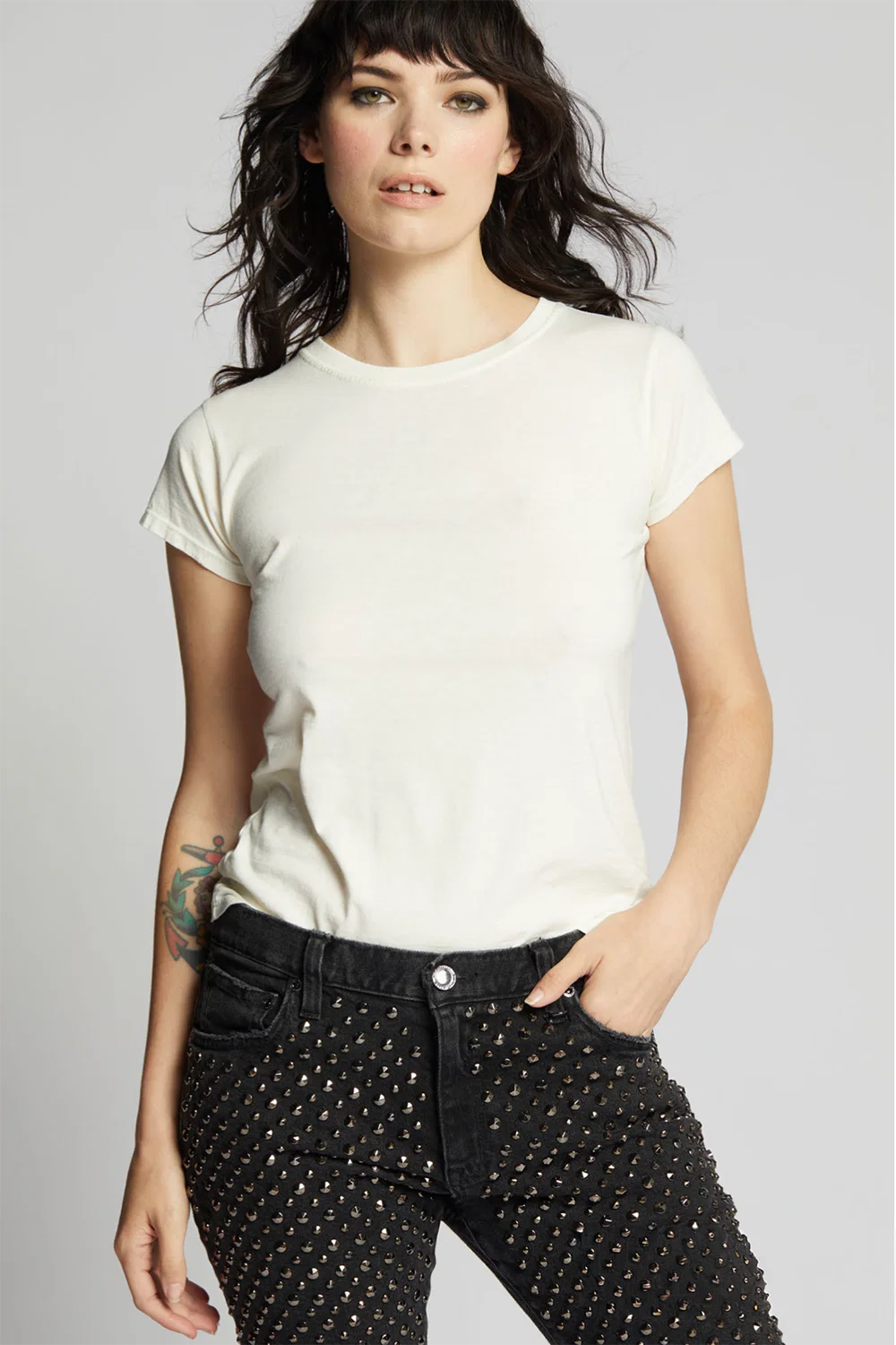 Woman wearing white tee and black pants on plain background